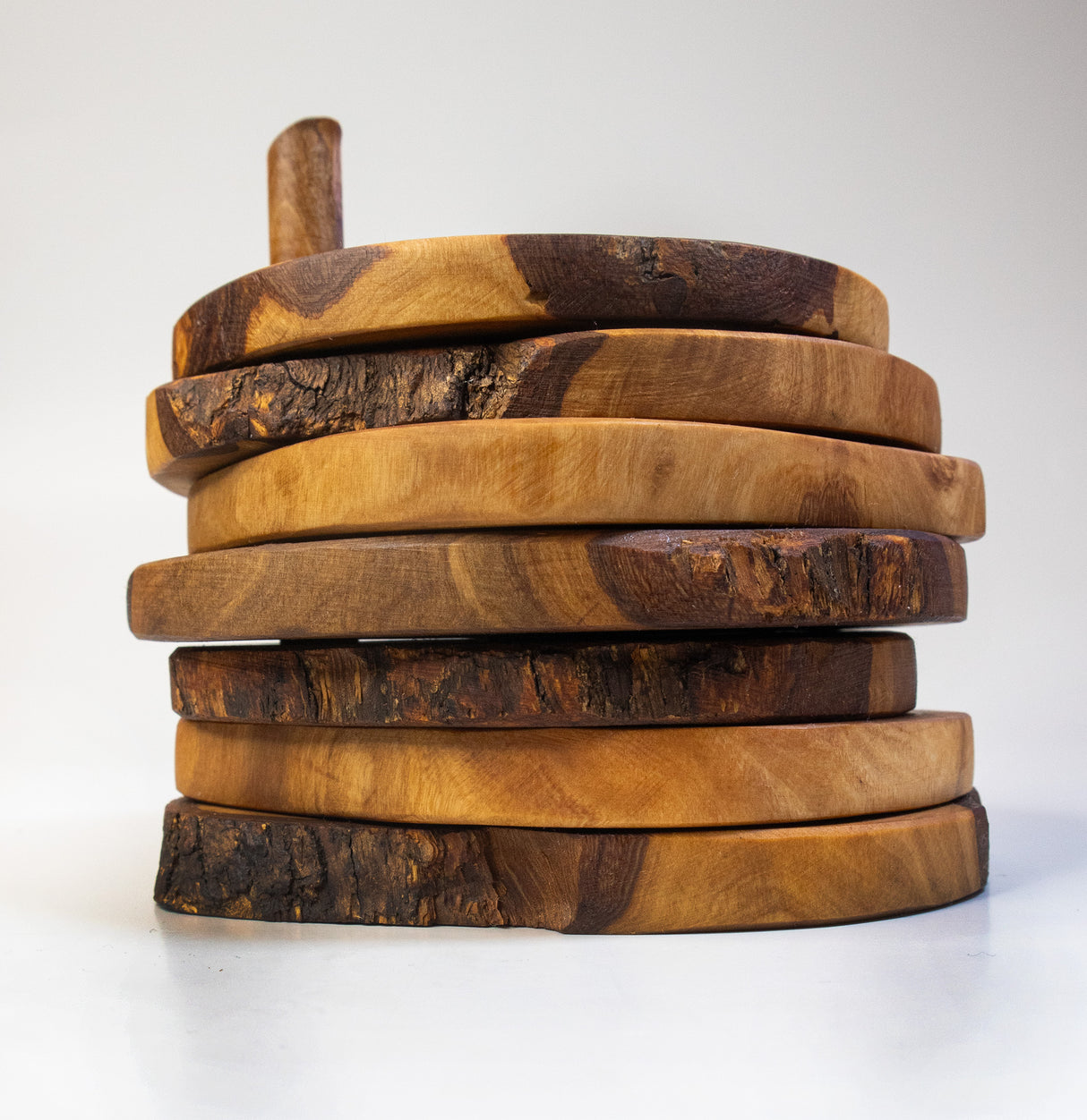 A stack of six olive wood coasters with a distinctive grain, displayed on a white background.